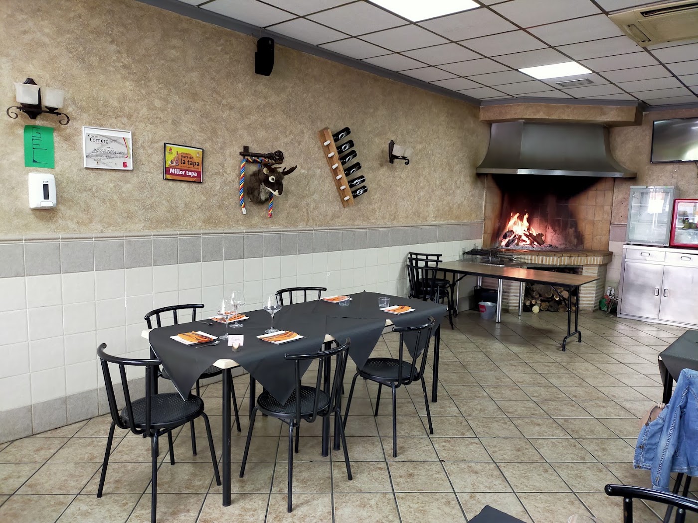 Comedor del Bar GIN con mesas y la zona de brasa al fondo